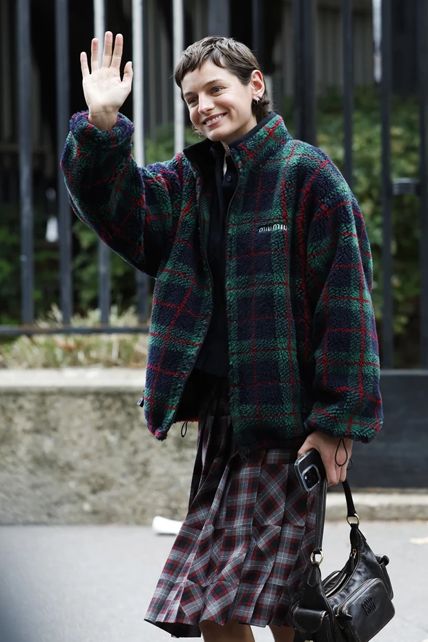 υναίκα με χοντρό, πράσινο-μπλε-κόκκινο καρό φλις τζάκετ και σκούρα καρό μίντι φούστα, χαιρετά.