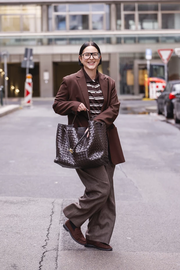 Γυναίκα με καφέ wide leg παντελόνι και loafers σε μονοχρωματικό σύνολο.