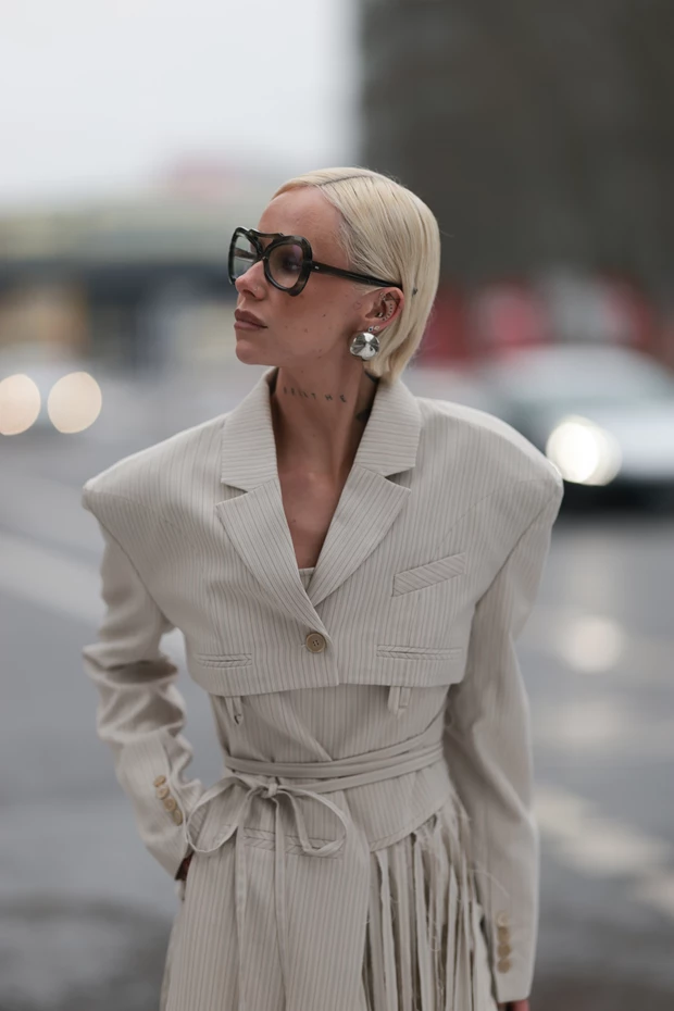 Γυναίκα με neutral κοστούμι statement σκουλαρίκια και γυαλιά ηλίου