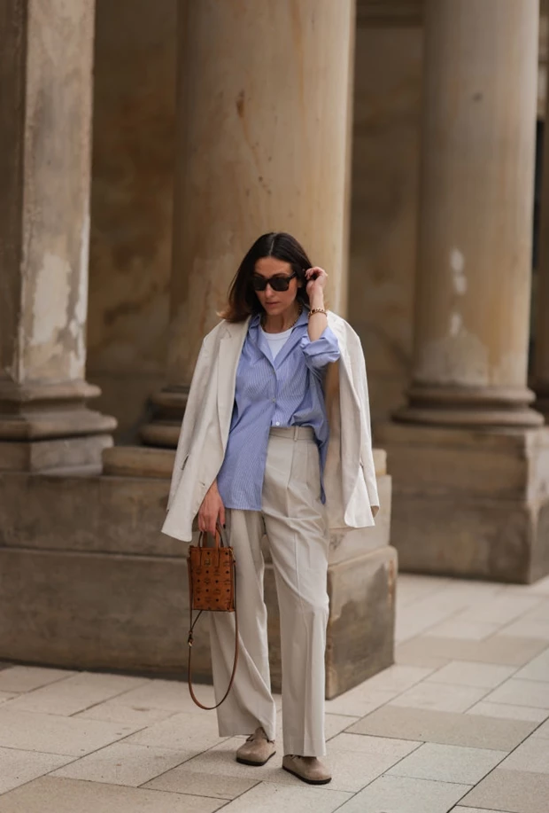 Street style γυναικείο look με λινό μπεζ σακάκι, ριγέ γαλάζιο πουκάμισο, παντελόνα και τσάντα ταμπά MCM.