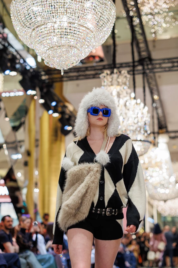 Εμφάνιση με γούνα και ρόμβους (διαμάντια): Ασπρόμαυρη ζακέτα, μπλε γυαλιά ηλίου και λευκό γούνινο καπέλο με pom poms, Golden Hall Fashion Show.