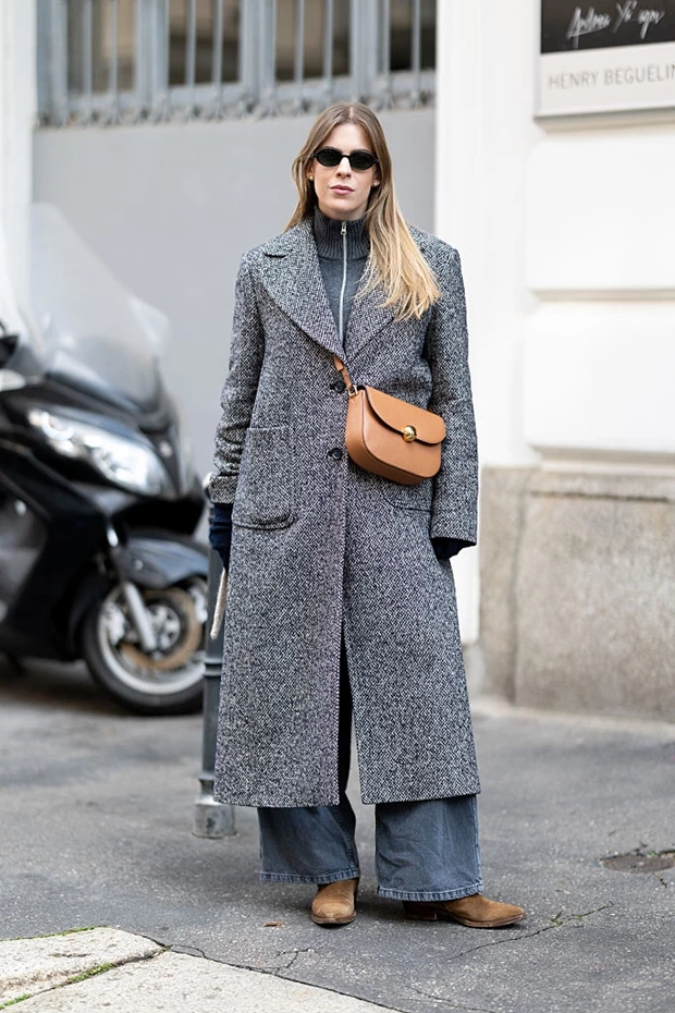 Γυναικείο layering look με γκρι πουλόβερ με φερμουάρ, μακρύ παλτό και τζιν παντελόνι.