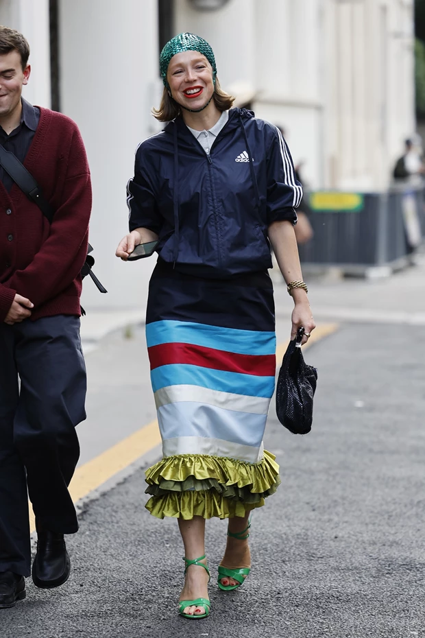 Στιλάτη εμφάνιση street style με μπλε αθλητικό μπουφάν, πολύχρωμη φούστα με βολάν και πράσινο σκουφάκι.