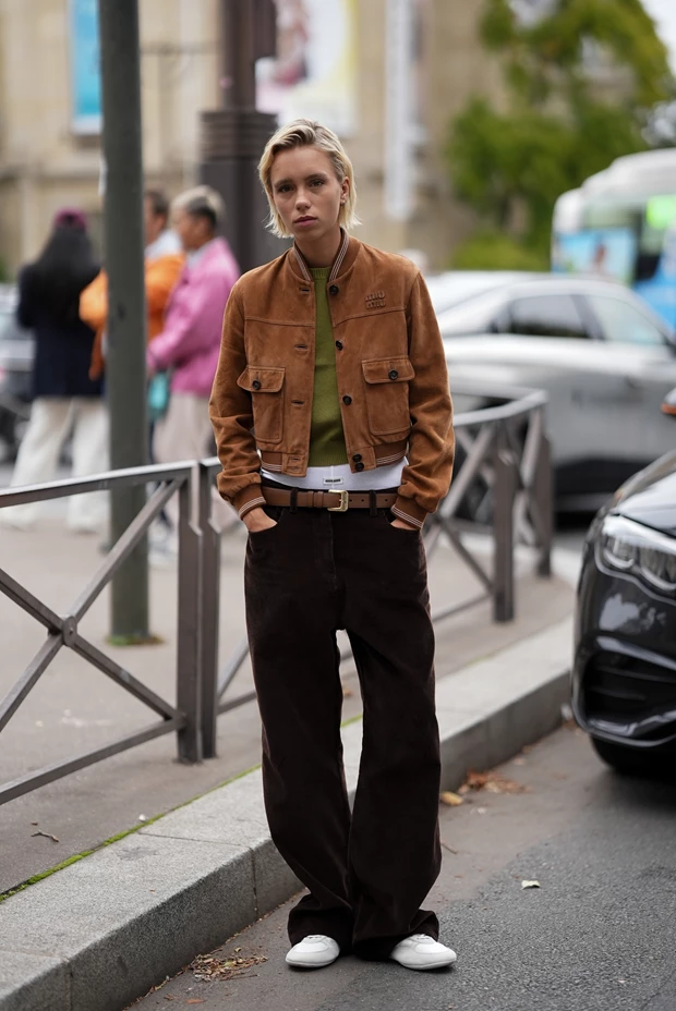 Γυναίκα με σουέτ jacket, μαύρο παντελόνι και λευκά sneakers, σε κομψό φθινοπωρινό street style σύνολο.