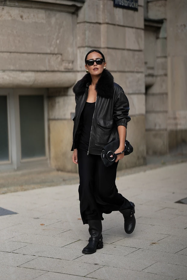Γυναίκα με μαύρο φόρεμα, δερμάτινο τζάκετ και biker μπότες για χειμώνα.