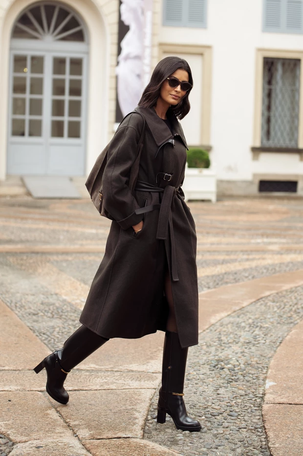 Chic εμφάνιση γυναίκες με παλτό σε σοκολατί χρώμα, φορεμένο με ψηλές μαύρες μπότες και ζώνη στη μέση.