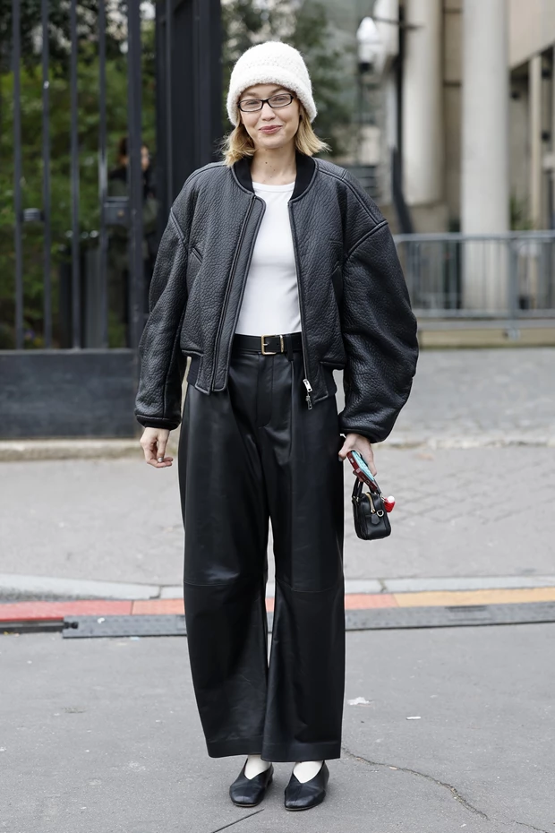 Γυναίκα με μαύρο wide leg παντελόνι και oversized bomber jacket σε urban look.