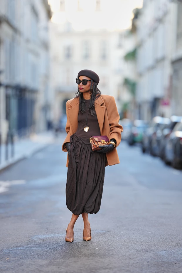 Γυναίκα με camel σακάκι και balloon μίντι φόρεμα σε σοκολατί απόχρωση.