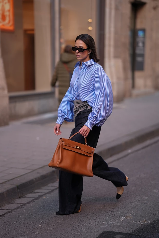 Minimal look με ριγέ πουκάμισο και loose παντελόνι, συνδυασμένο με καφέ δερμάτινη structured τσάντα σε quiet luxury αισθητική