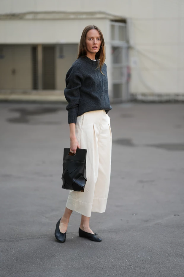 Γυναίκα με μαύρες μπαλαρίνες, λευκό παντελόνι και γκρι πλεκτό σε minimal street style look