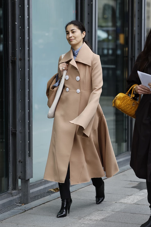 Γυναίκα με κομψό μπεζ παλτό και μαύρες μπότες στο Παρίσι.