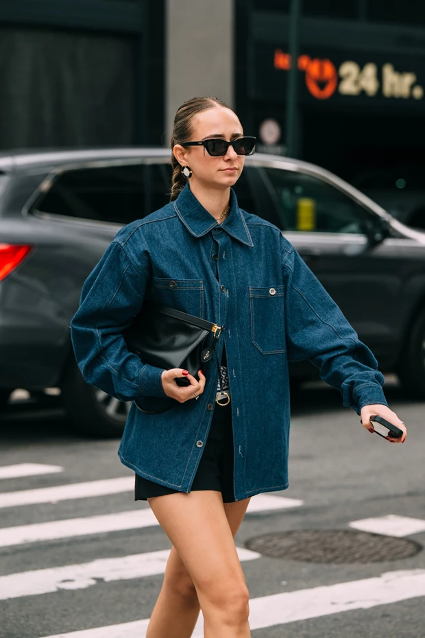 Γυναίκα με μαύρο σορτς, denim shirt και clutch.