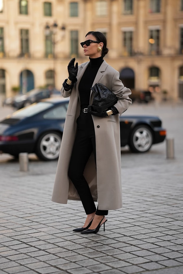 Minimal μαύρη δερμάτινη τσάντα φακέλος σε ένα κομψό street style look με γκρι παλτό και μαύρο ζιβάγκο