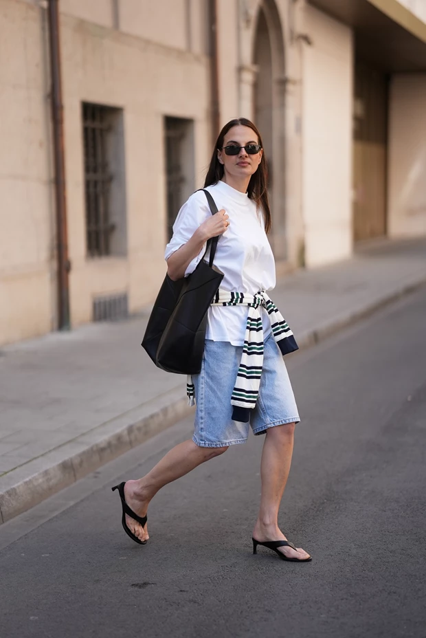 Γυναίκα με denim βερμούδα, λευκό τοπ και kitten heel