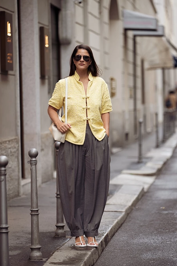 υναίκα φοράει γκρι balloon παντελόνι με κίτρινο jacket και λευκά πέδιλα σε δρόμο του Μιλάνου.