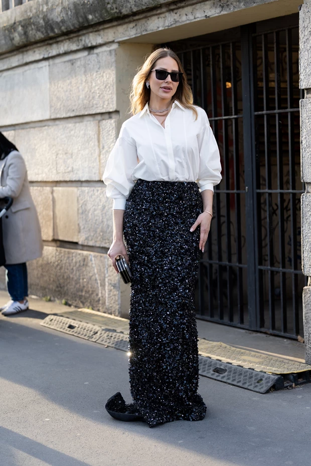 Γυναίκα με μακριά, στενή φούστα με μαύρες παγιέτες, συνδυασμένη με λευκό πουκάμισο και μαύρο clutch.