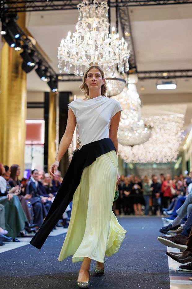 H Ισμήνη Παπαβλασοπούλου με λευκό, μαύρο και κίτρινο φόρεμα με πλισέ φούστα στην πασαρέλα του Golden Hall, Stay Golden Fashion Show.