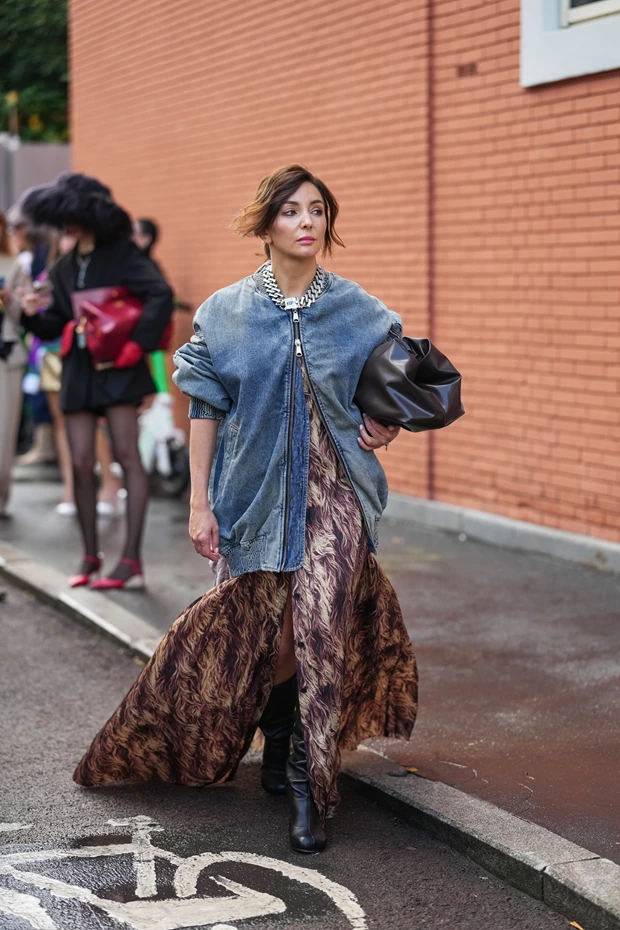 Γυναίκα με oversized denim bomber jacket πάνω από μάξι printed φόρεμα