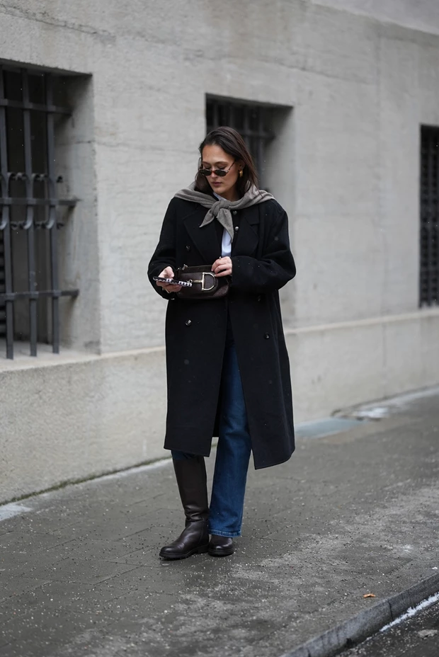 Chic χειμερινό look με κλασικό μπλε stovepipe τζιν συνδυασμένο με καφέ δερμάτινες μπότες και μαύρο μάξι παλτό.