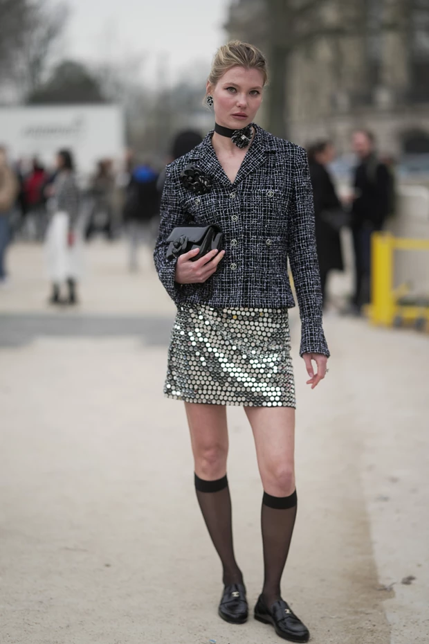 Μοντέλο με κοντή, ασημένια φούστα με μεγάλες παγιέτες, συνδυασμένη με μπλε-μαύρο τουίντ σακάκι.