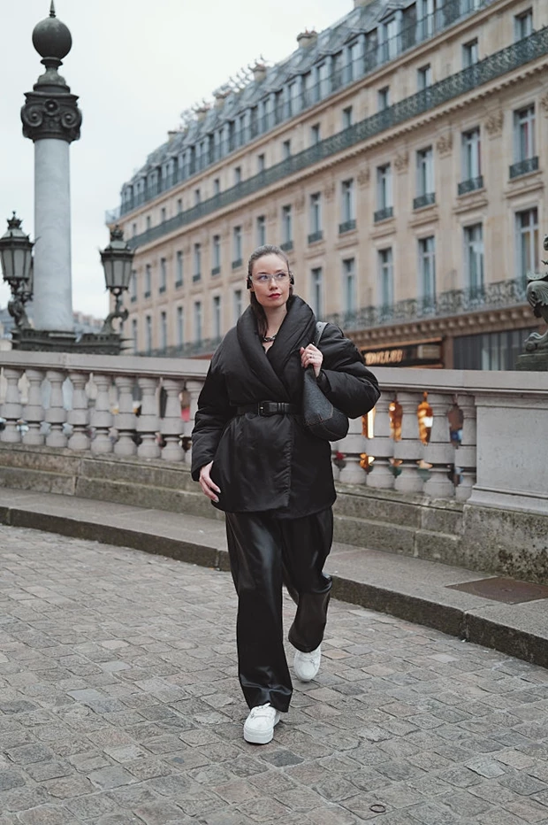 Urban chic σύνολο με μαύρο oversized φουσκωτό jacket (puffer) που κλείνει με ζώνη στη μέση, συνδυασμένο με φαρδύ δερμάτινο παντελόνι.