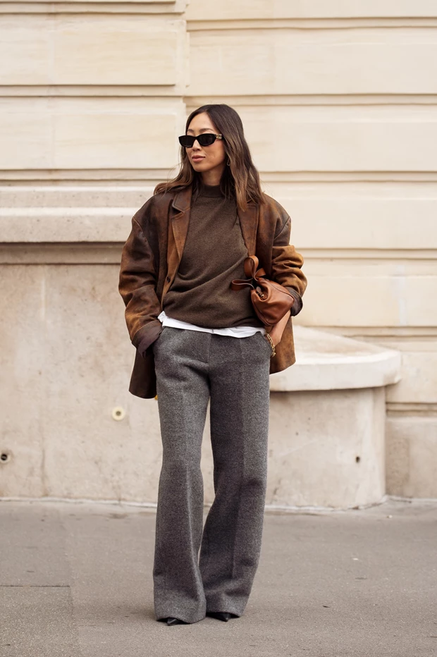 Γυναίκα που φοράει καφέ πουλόβερ, γκρι μάλλινο παντελόνι και σουέτ σακάκι.