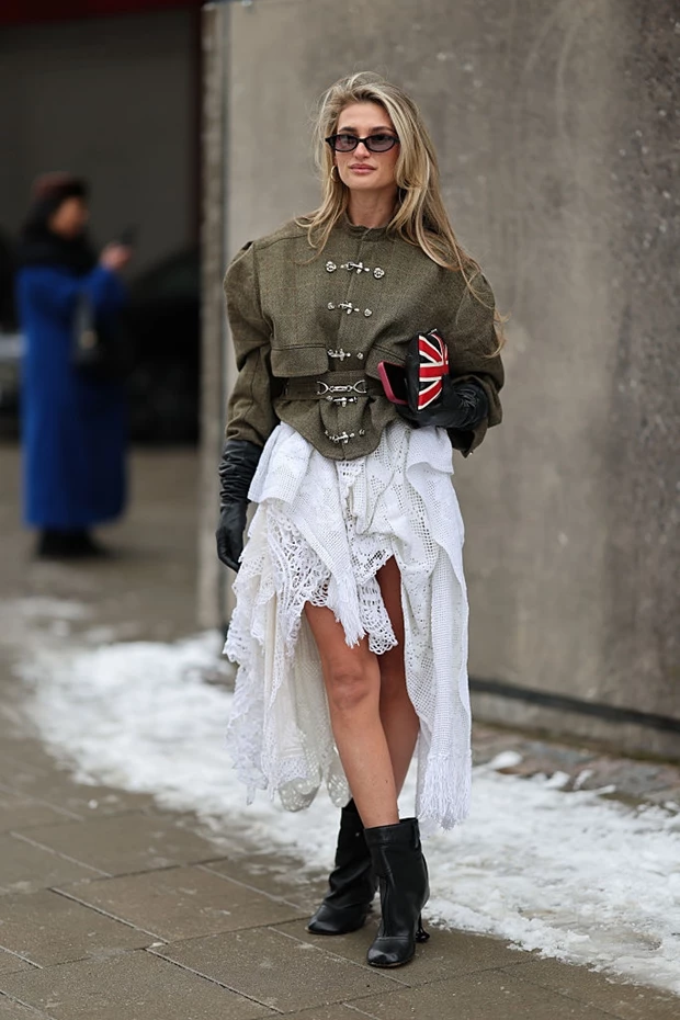 Γυναίκα στον δρόμο που φοράει ασύμμετρη φούστα και χακί τζάκετ.