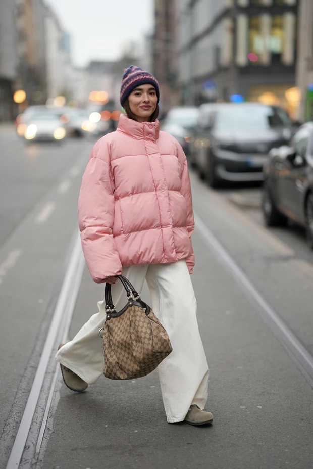 Street style εμφάνιση με μπεζ σουέντ clogs, λευκό φαρδύ παντελόνι και oversized ροζ φουσκωτό μπουφάν