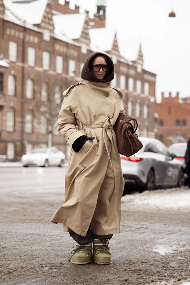 Χειμερινό look με μπεζ trench coat, κουκούλα και chunky μπότες σε street style εμφάνιση στην Κοπεγχάγη