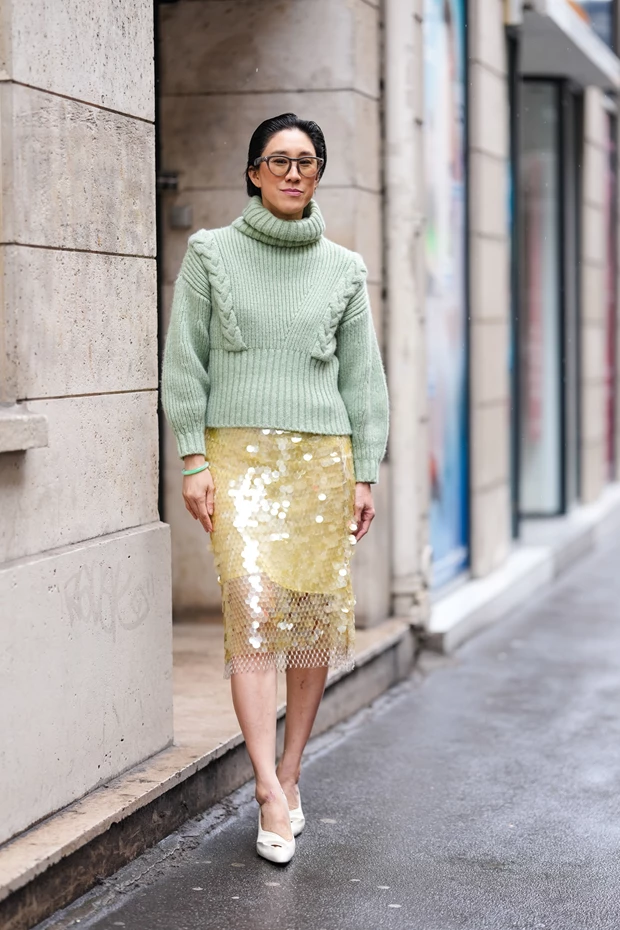 Γυναίκα φοράει φούστα με παγιέτες και πουλόβερ oversized σε comfort glam look.